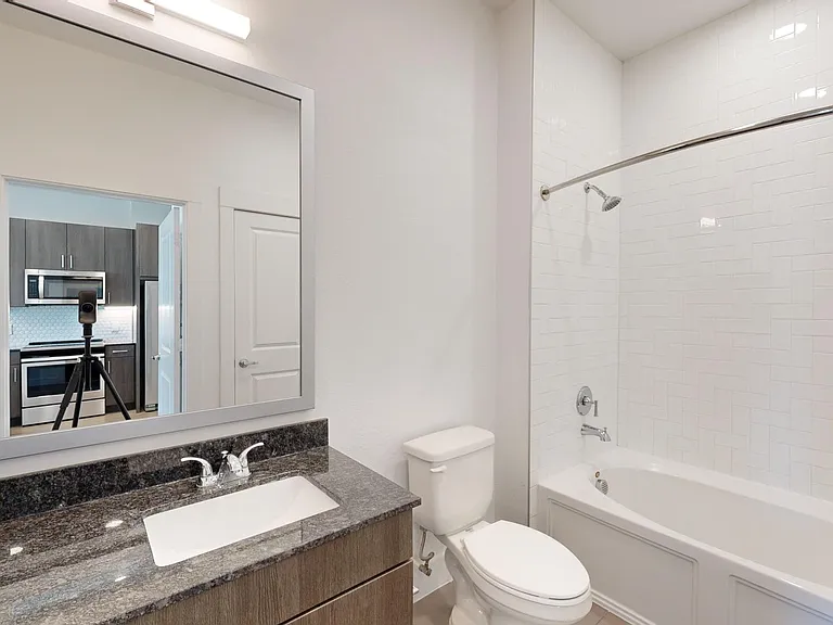 Apartment bathroom with large soaking tub and tile flooring.