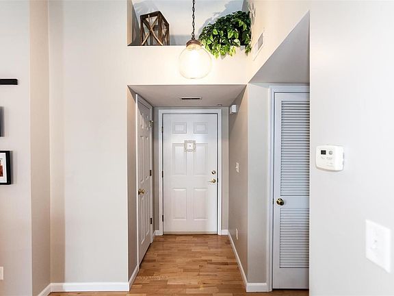 Entry foyer features hard wood flooring, hall closet and plant shelf.
