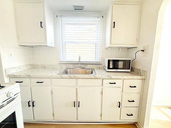 First floor _ newly renovated kitchen with brand-new French-door refrigerator, 4-burner stove, microwave and modern countertops, offering a clean and functional cooking space.