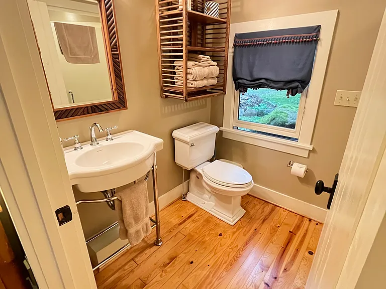 Sparklingly clean bathroom with shelving above toilet and below sink for storage.