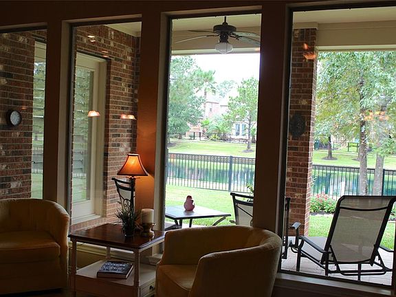 A gem of a home in the unique gated community in the Champions Area. This is the view from inside the home looking out onto the covered patio on the back of this home, and onto the tranquil lake. On the left is the walk out from the breakfast room to