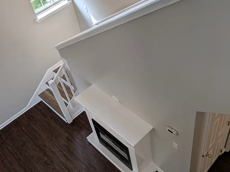 View from the upper landing showing the open floor plan, fireplace, and rich wood-style flooring