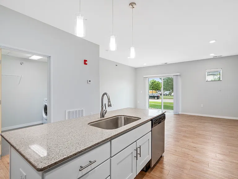 Bright modern open-concept kitchen with sleek island sink, elegant pendant lighting, and spacious living area leading to a scenic patio view. Bright modern open-concept kitchen with sleek island sink, elegant pendant lighting, and spacious living area lea