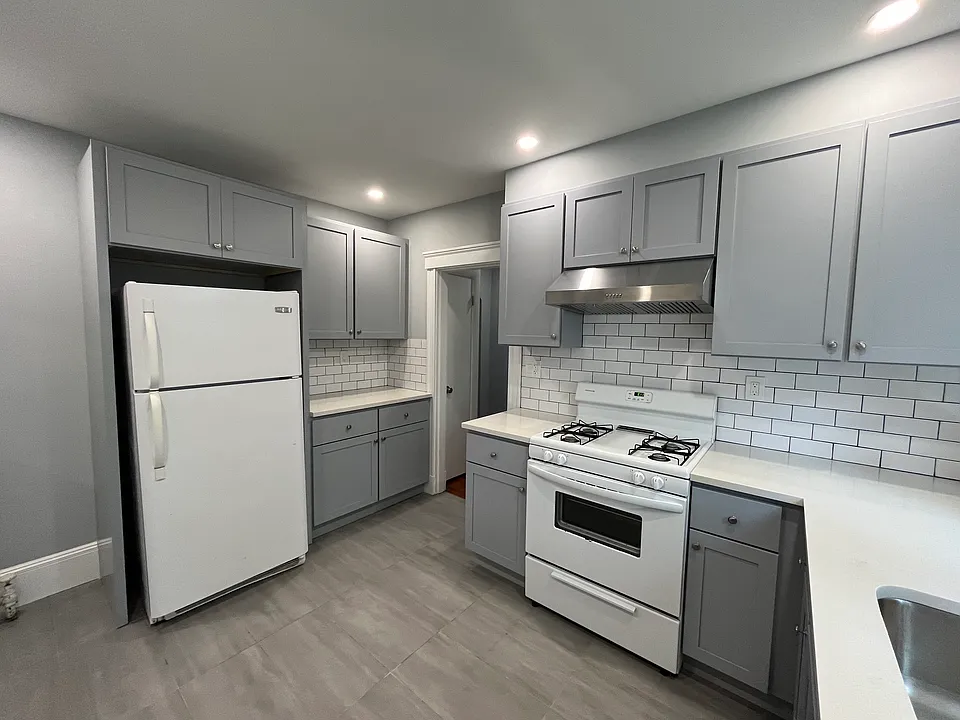 Newly renovated kitchen with new kitchen cabinets, quartz countertops, tile floors and backsplash, new electrical work and plumbing, and recessed lighting