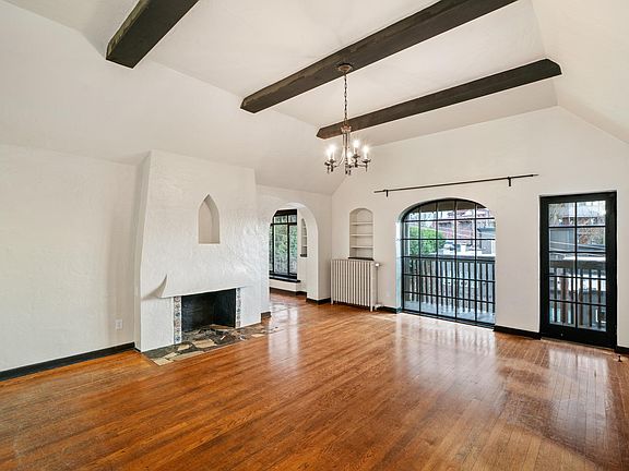 Spacious living room, 10-foot vaulted and beamed ceiling. Faux decourative fireplace. Hardwood floors. Balcony access with southern and west views of South Lake Union, Olympic Mountain and sunsets.
