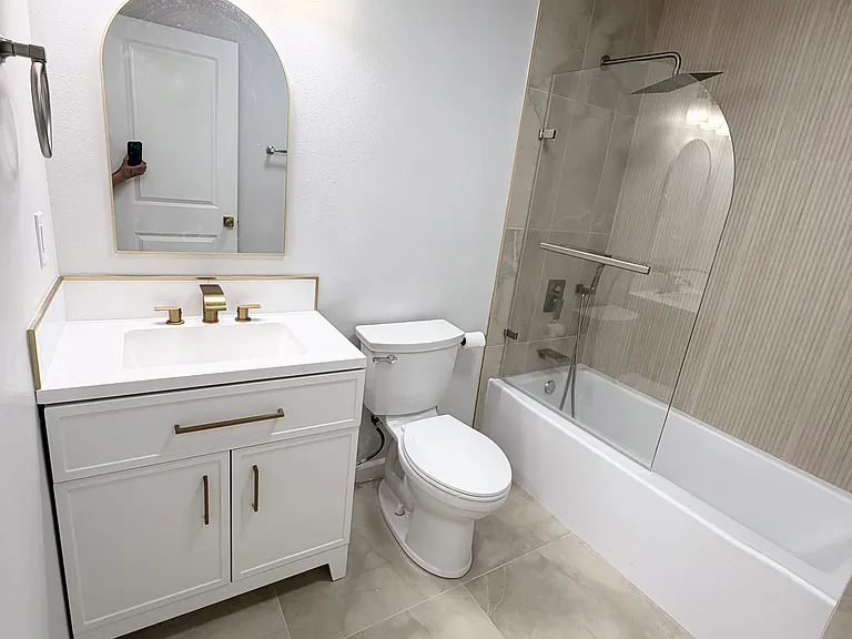 Bathroom ~ 
This updated bathroom features elegant tile flooring, tiled shower walls, a modern shower door, and an additional wall heater for enhanced comfort and convenience.