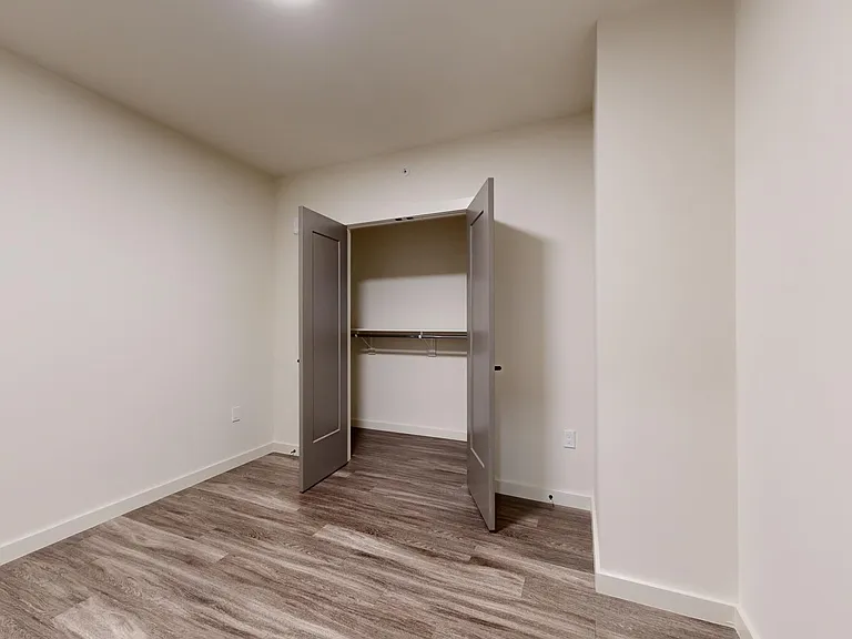 Spacious apartment bedroom with wood-style flooring.