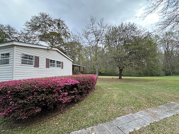 View along the front of the house with the expansive fenced yard and large oaks in the background.