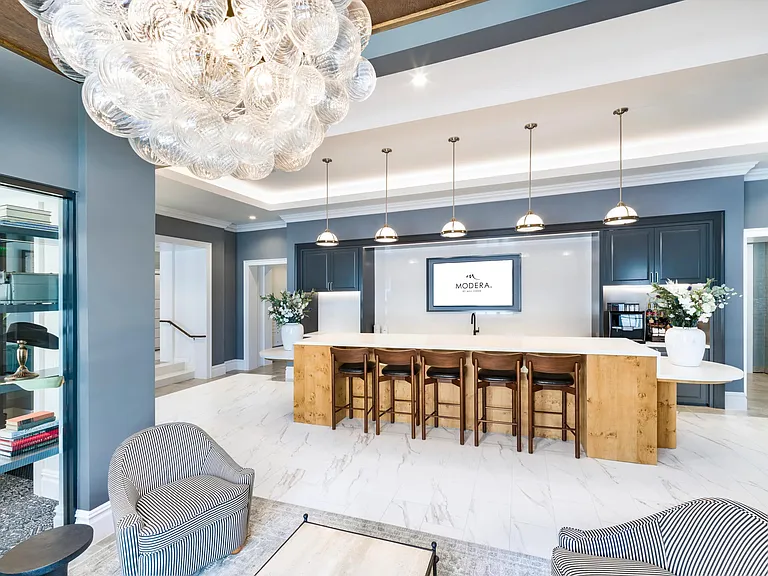 Dual-purpose coworking lounge and demonstration kitchen with bar seating, and sculptural lighting designed for a focused work retreat.