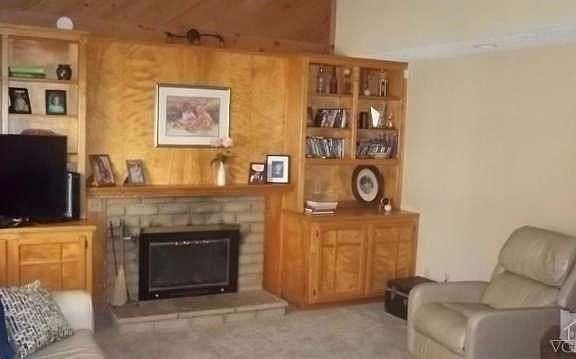 Step-down living room with vaulted ceiling, brick fireplace with gas starter, builtin cabinets and b
