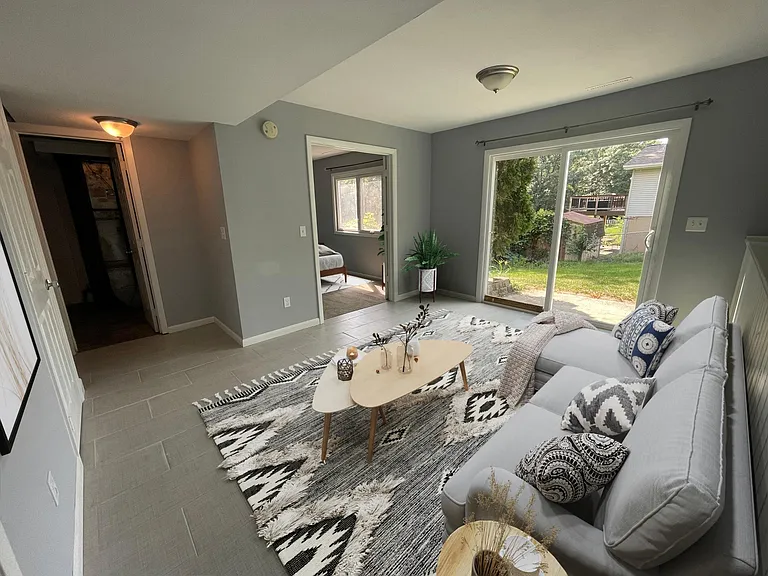 Open area in the lower level of the home. Left door is the laundry/utility room and the patio door leads to the backyard.