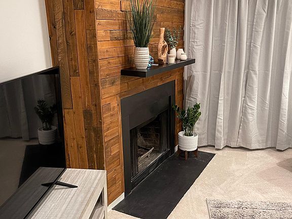 The fireplace hearth is decorated with wood for a rustic vibe.