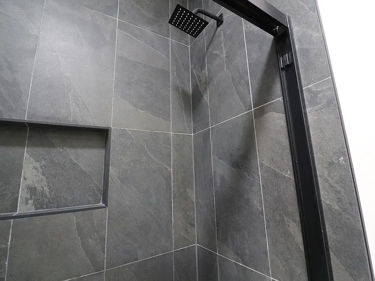 Contemporary shower featuring elegant tile, a built-in niche, and a modern rainfall showerhead.