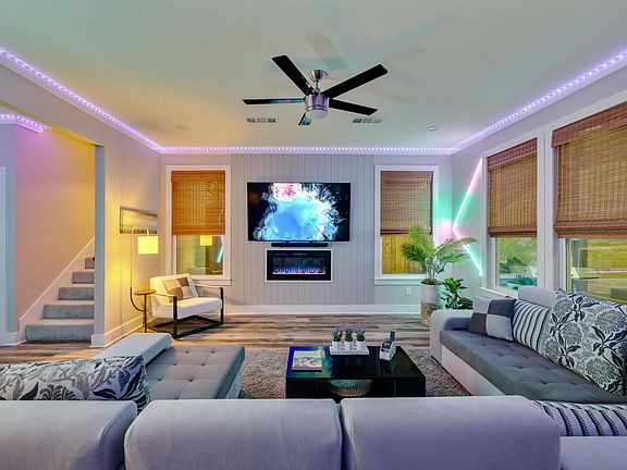 Modern living room sectional and custom chair. 75" tv, electric fireplace, speaker/sound bar, with custom wall and ceiling lighting.