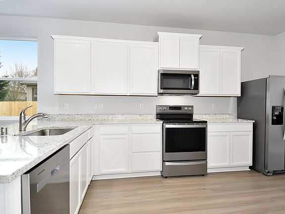 The kitchen has stainless steel appliances and plank flooring.