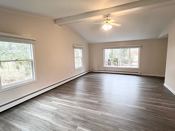 Large Living room with cathedral ceiling and bay window adjacent to kitchen.