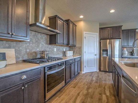 Chef kitchen with staggered cabinets, quartz countertops and stainless steel appliances