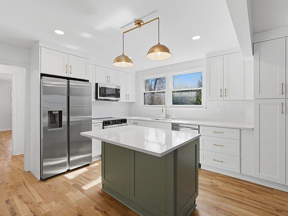 Brand new stainless steel kitchen appliances with custom cabinetry and quartz countertops