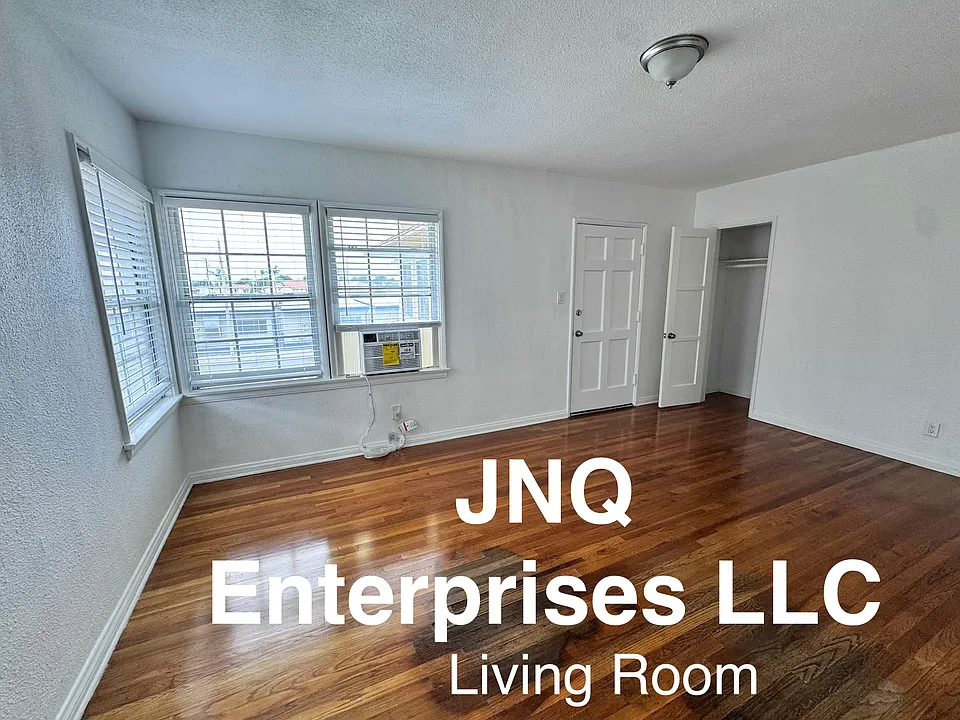 Freshly painted comfortable size living room with new air conditioner and refinished hardwood floors.