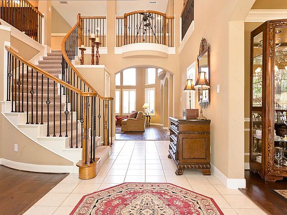 Elegant foyer with Tuscan finished walls and ceramic tile flooring.  Sweeping wrought iron staircase with views of the second floor.