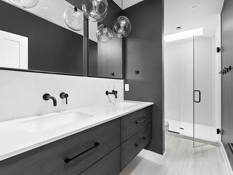 Primary bathroom with double vanity, walk in shower with skylight