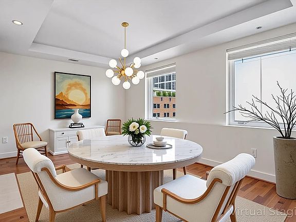 Dining area featuring a tray ceiling, wood finished floors, a chandelier, and recessed lighting