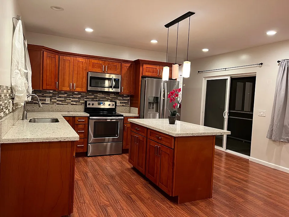 Such a pretty kitchen! Kitchen Island for dining and food preparation. Stainless steel fridge, stove & microwave appliances