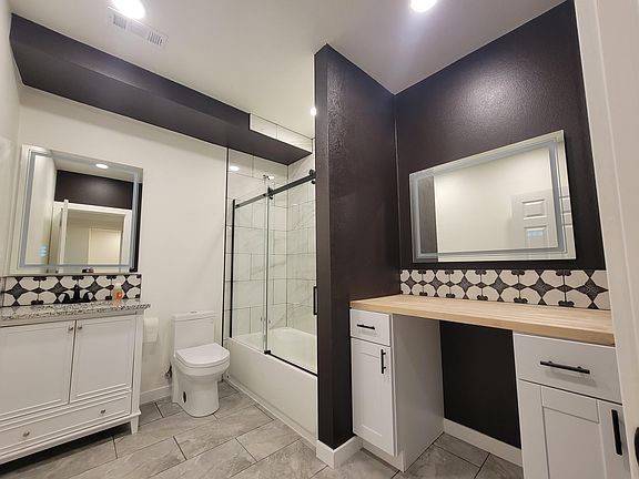 Brand new bathroom with tub, lighted mirrors, low-flow toilet, and designated storage space.