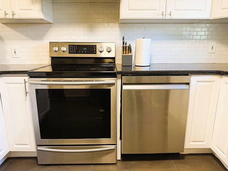 Kitchen features stainless steel range and dishwasher, ample cabinetry, and a subway-tile backsplash with generous counter sp