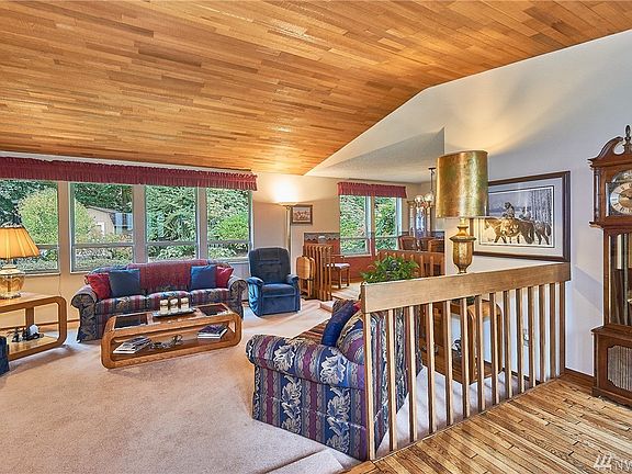 Living room with vaulted ceiling, lots of natural light and warm natural wood accent.