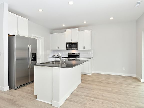 The kitchen has stainless steel appliances and plank flooring.
