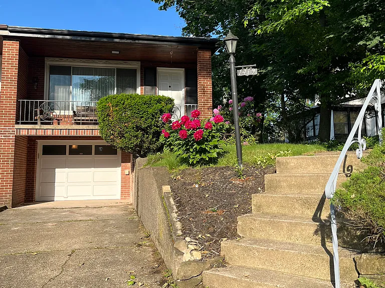 Front of house with full-width porch, garage, and driveway