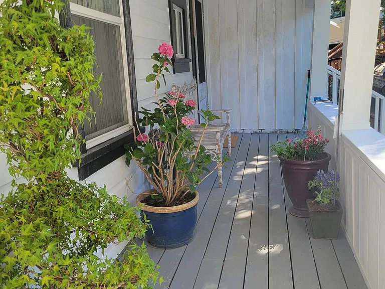 Picture of side covered porch when owner lived here. Plants not included.