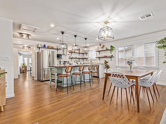 Open-concept kitchen and dining room with dining table that seats 6 and bar/island that seats 4. Stainless steel appliances.