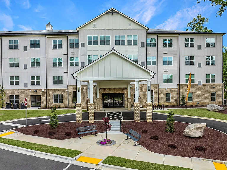 Active Adult Community with an exterior view of an apartment building with a courtyard and benches
