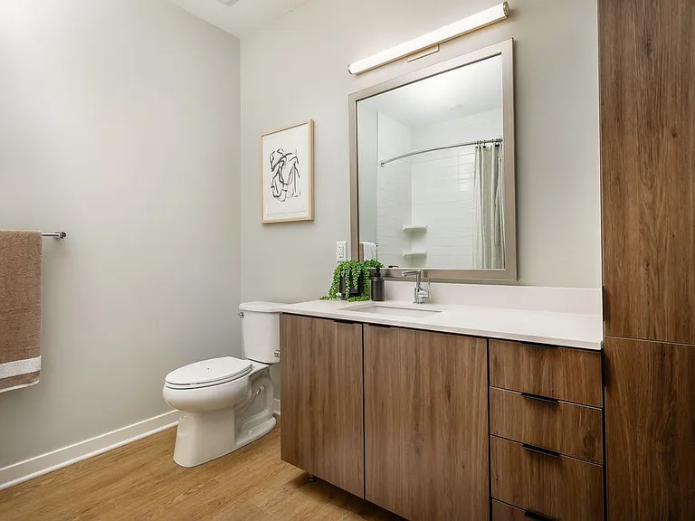 Upgraded Collection bath with neutral quartz countertops, dark brown cabinetry, and hard surface flooring (model home)