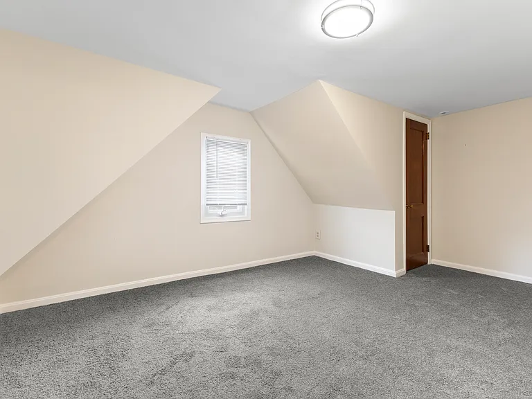 Spacious upstairs bedroom with unique sloped ceilings and plush new carpeting.