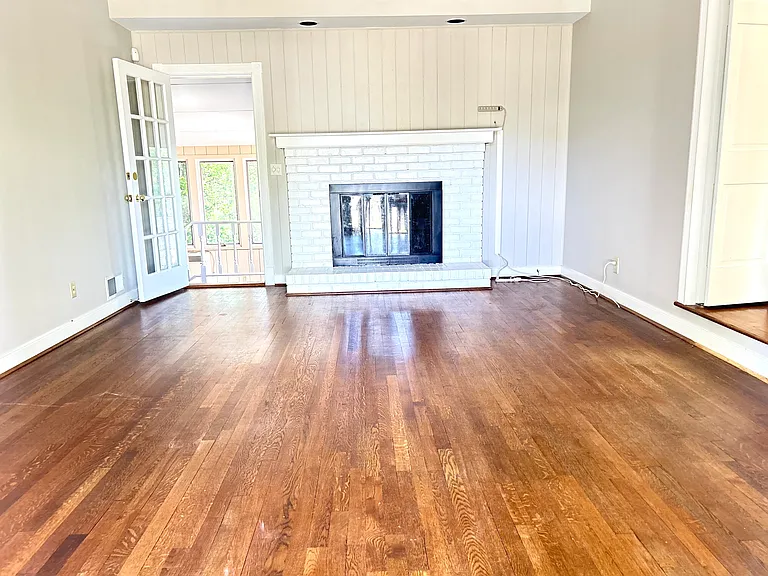 Bright and large living room with a fireplace, access to the sunroom and the kitchen.