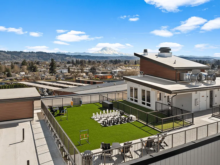 Elevated outdoor space in Sumner, WA featuring lawn games, seating, scenic views, and a rooftop pet area.
