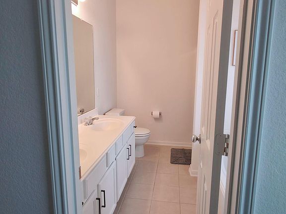Full bathroom with wide vanity, ample cabinet storage, and easy-clean tile flooring for everyday convenience.