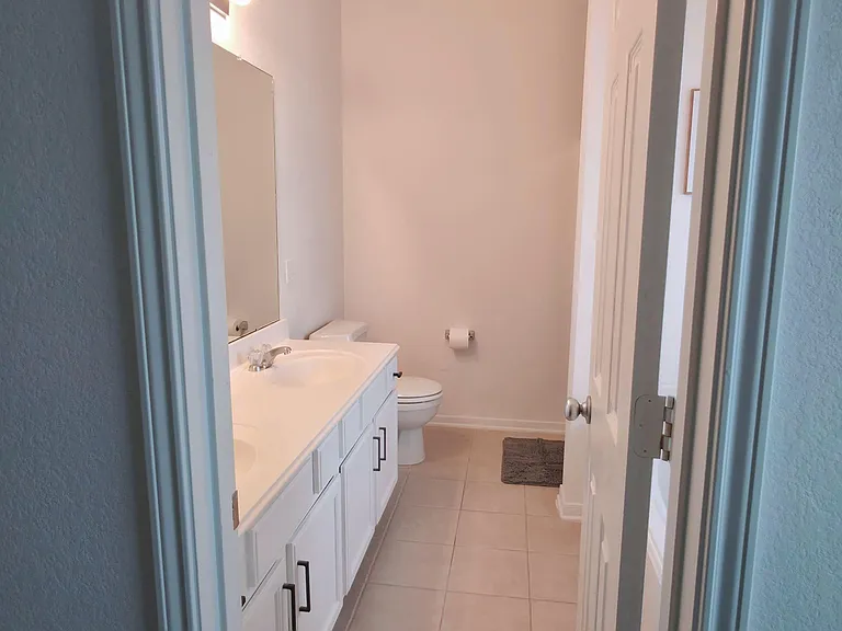 Full bathroom with wide vanity, ample cabinet storage, and easy-clean tile flooring for everyday convenience.