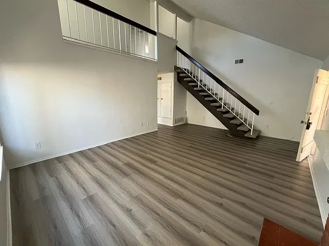Living room with stairwell, front door seen in the right of this picture
