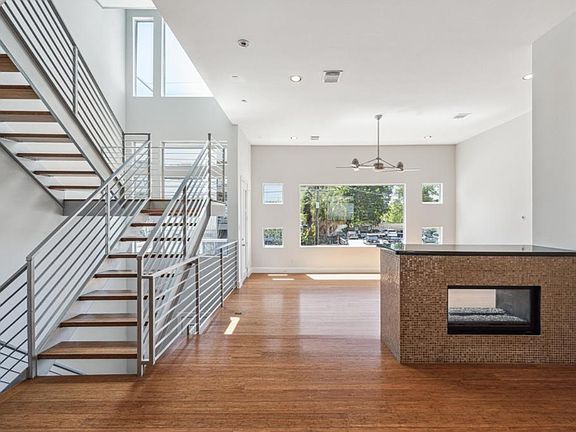 The kitchen and living room flow effortlessly together, highlighted by stunning hardwood floors that extend throughout the space. Large front windows fill the home with natural light, while the fireplace adds warmth and charm to the living and dining room