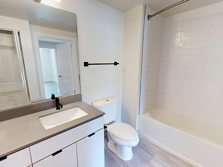 Apartment bathroom with soaking tub and wood style floor.
