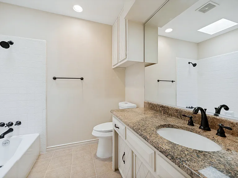 Guest bathroom with tub / shower and granite countertops.