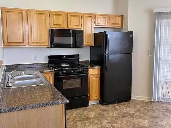 Spacious kitchen with faux granite looking counters, black appliances, gas range and built in microwave.