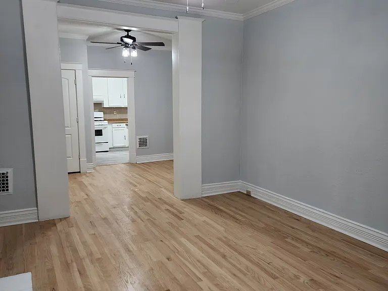 View of front room walking into the apartment. Newly refinished hardwood floors and new ceiling fixtures throughout
