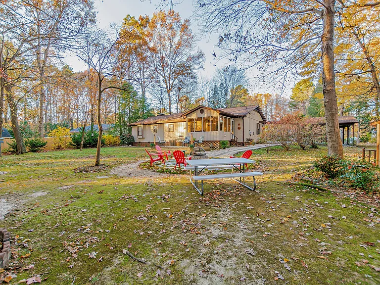 Back of the home showing the sun room, fire ring, and picnic tables.