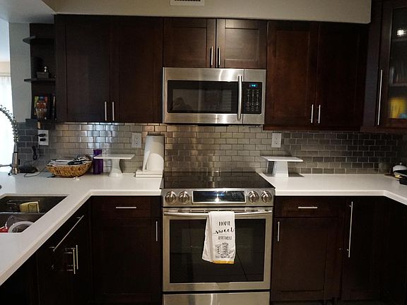 Spacious Kitchen with Stainless steel appliances, wood cabinets and quartz countertops.