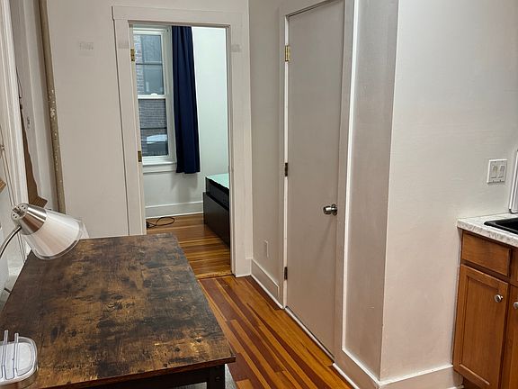Side of kitchen with table and two stools - can be used as a table, desk, or prep space. The door in the right is to the bathroom, and the opened door is the back bedroom.